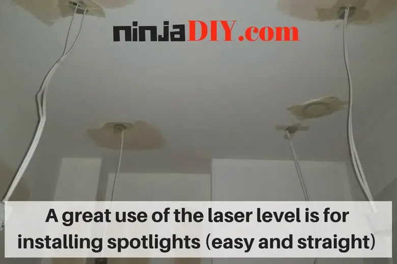 ceiling works installing spotlights using a laser level for electricians